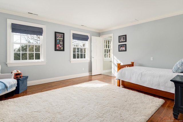 bedroom with wood finished floors, visible vents, baseboards, and multiple windows