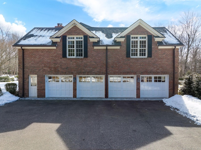 view of home's exterior featuring a chimney, aphalt driveway, and brick siding