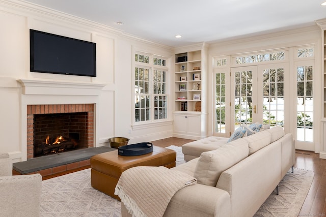 living area with a fireplace, built in features, wood finished floors, and recessed lighting