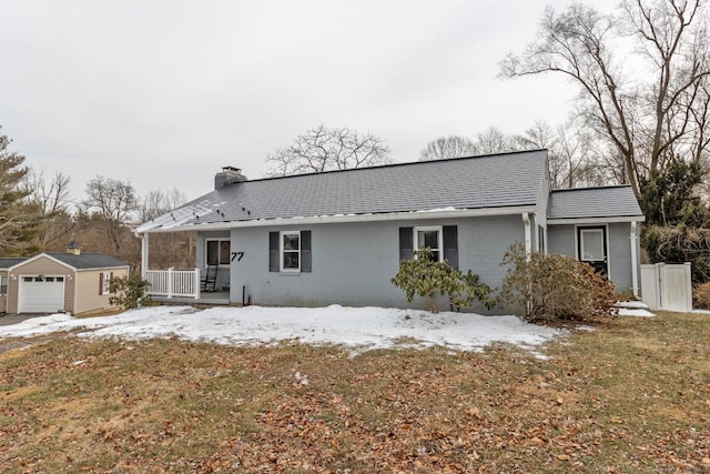 view of front of home with an outbuilding, a garage, covered porch, and a lawn