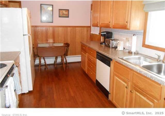 kitchen with a baseboard radiator, sink, dark wood-type flooring, and white appliances