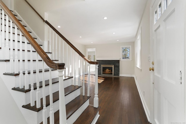 entryway with recessed lighting, a warm lit fireplace, baseboards, and hardwood / wood-style flooring