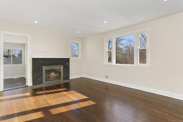 unfurnished living room featuring a fireplace with flush hearth, wood finished floors, and baseboards