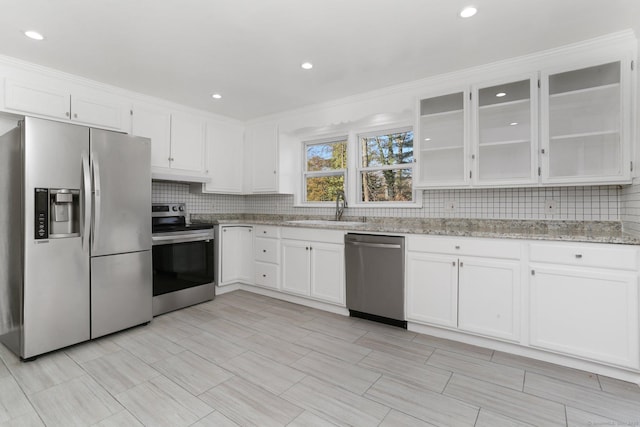 kitchen featuring glass insert cabinets, white cabinetry, appliances with stainless steel finishes, and a sink