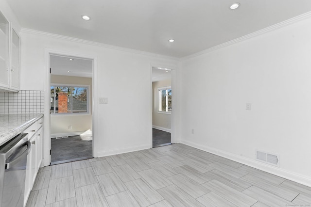 interior space with ornamental molding, a wealth of natural light, visible vents, and baseboards