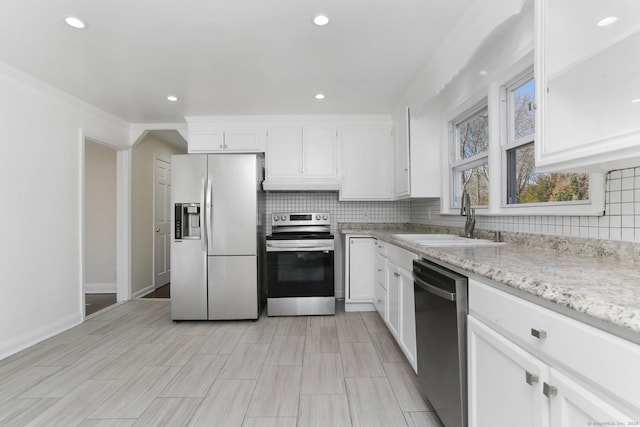 kitchen with appliances with stainless steel finishes, backsplash, a sink, and white cabinetry