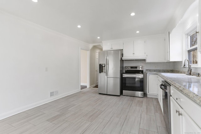 kitchen featuring stainless steel appliances, visible vents, decorative backsplash, white cabinetry, and a sink