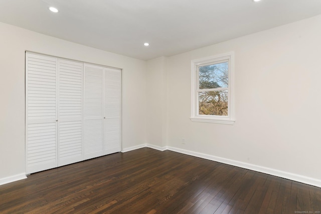 unfurnished bedroom with dark wood-style floors, a closet, recessed lighting, and baseboards