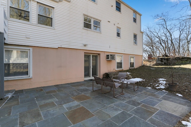 rear view of house with an AC wall unit, a patio area, and stucco siding