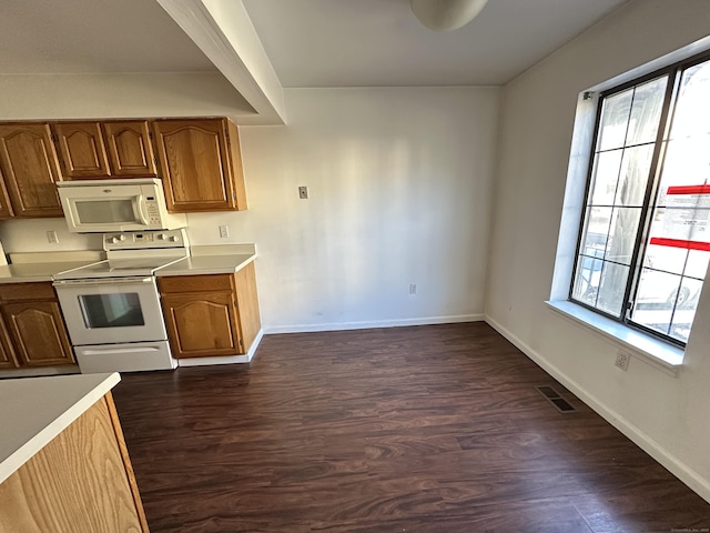 kitchen featuring dark hardwood / wood-style flooring, a wealth of natural light, and white appliances