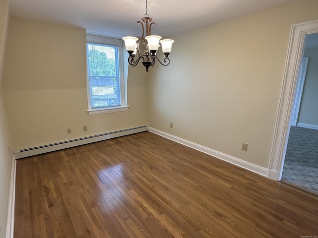 spare room with a chandelier, hardwood / wood-style floors, and a baseboard heating unit