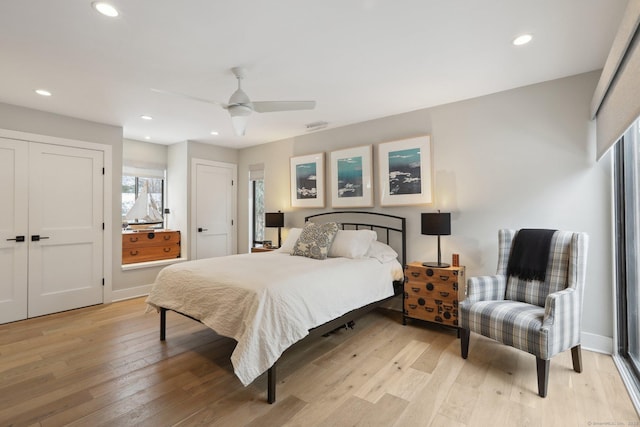 bedroom featuring multiple closets, ceiling fan, and light wood-type flooring