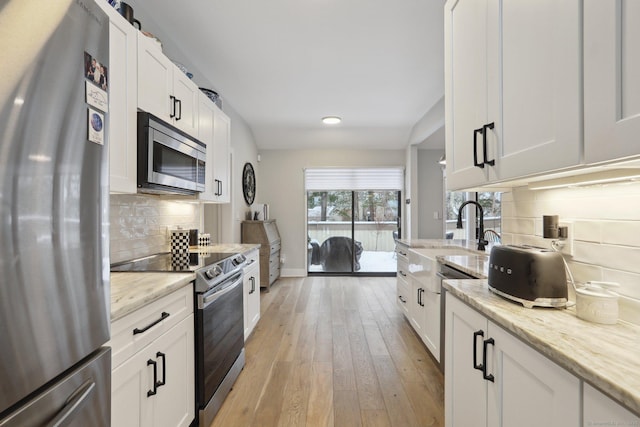 kitchen featuring light stone counters, sink, stainless steel appliances, and white cabinets