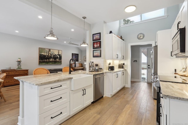 kitchen featuring hanging light fixtures, white cabinetry, appliances with stainless steel finishes, and kitchen peninsula