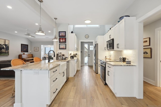 kitchen featuring decorative light fixtures, a breakfast bar, white cabinets, and appliances with stainless steel finishes