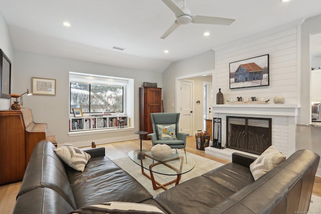 living room featuring vaulted ceiling, a brick fireplace, ceiling fan, and light hardwood / wood-style floors