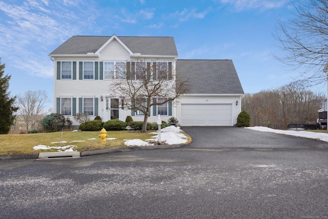 colonial inspired home with a garage and a front yard