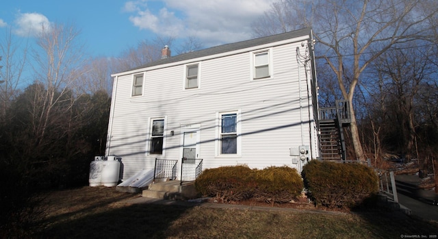 rear view of property featuring stairs and a chimney