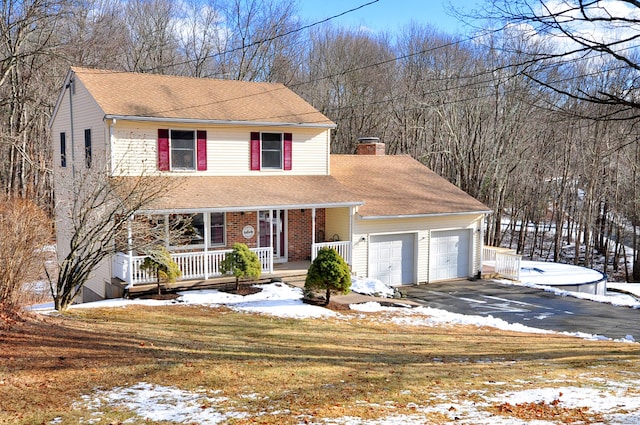 view of property with a garage, a yard, and covered porch