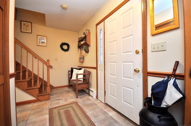 foyer entrance with light tile patterned floors, a textured ceiling, and baseboard heating