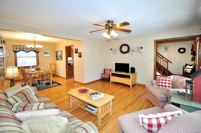 living room with ceiling fan with notable chandelier and hardwood / wood-style floors