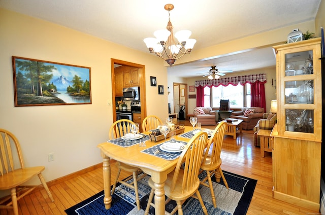 dining room with ceiling fan with notable chandelier and light hardwood / wood-style floors