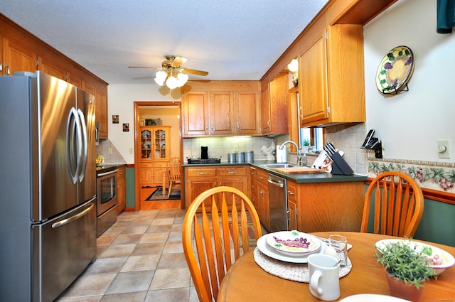 kitchen with appliances with stainless steel finishes, tasteful backsplash, sink, light tile patterned floors, and ceiling fan