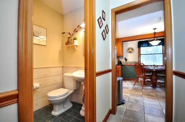 bathroom with tile patterned flooring, wooden walls, and toilet