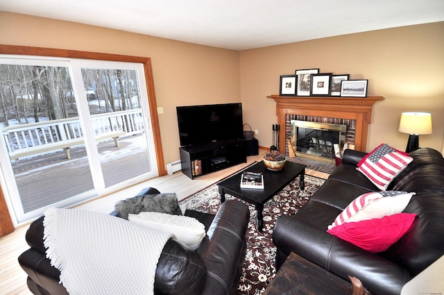 living room with a brick fireplace, a baseboard radiator, and hardwood / wood-style floors