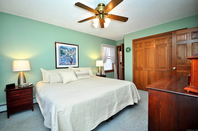 bedroom with a baseboard radiator, carpet flooring, ceiling fan, a textured ceiling, and a closet