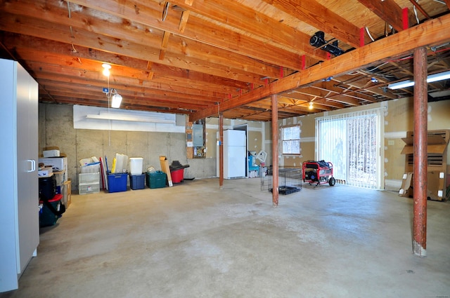 basement with white refrigerator and electric panel