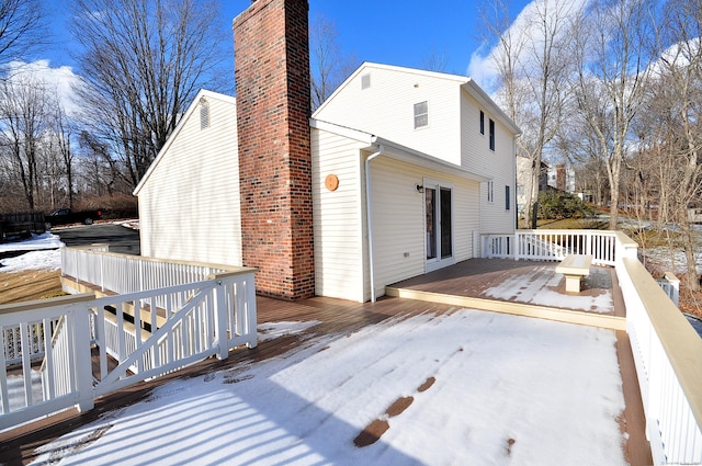 snow covered rear of property with a deck