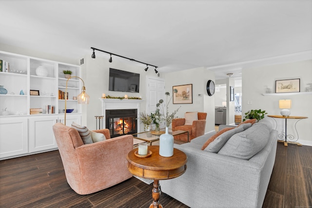 living room with dark wood-type flooring and rail lighting