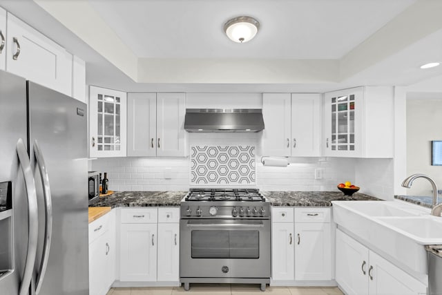 kitchen featuring appliances with stainless steel finishes, dark stone countertops, and white cabinets