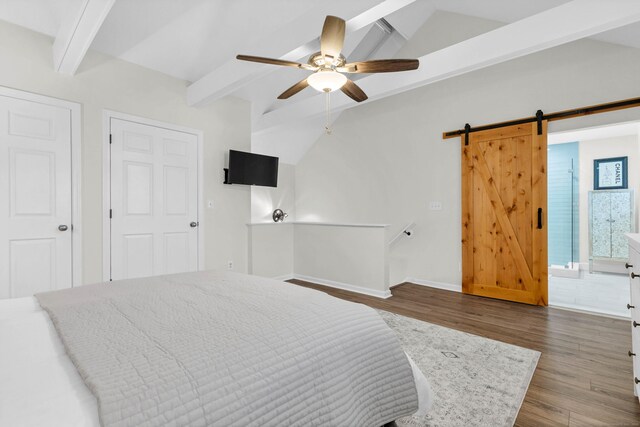 bedroom featuring connected bathroom, lofted ceiling with beams, ceiling fan, a barn door, and hardwood / wood-style floors