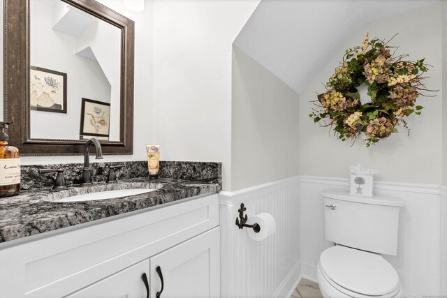 bathroom with lofted ceiling, vanity, and toilet