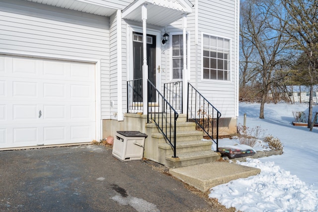 snow covered property entrance featuring a garage