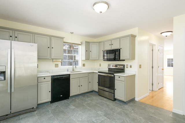 kitchen featuring hanging light fixtures, sink, gray cabinets, and black appliances