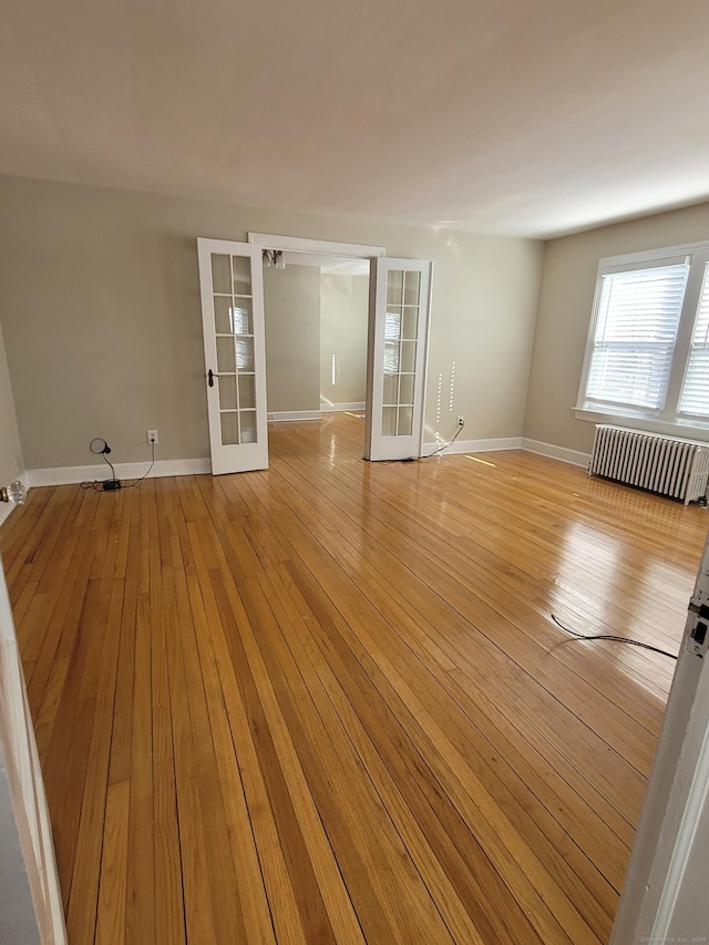 unfurnished room with french doors, radiator, and light hardwood / wood-style floors