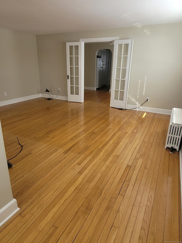 spare room featuring french doors and light hardwood / wood-style flooring