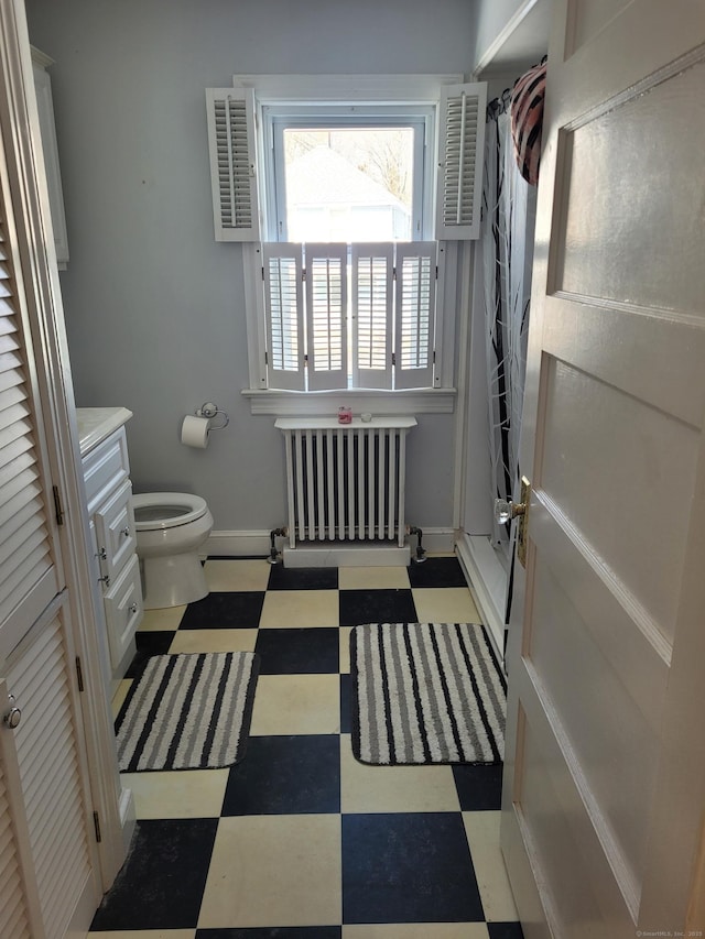 bathroom featuring vanity, radiator, toilet, and walk in shower