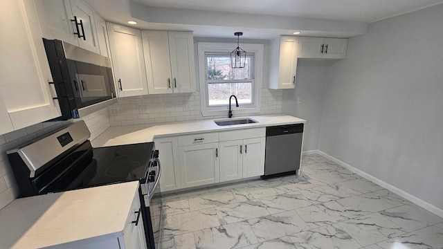 kitchen featuring sink, appliances with stainless steel finishes, white cabinetry, decorative backsplash, and decorative light fixtures