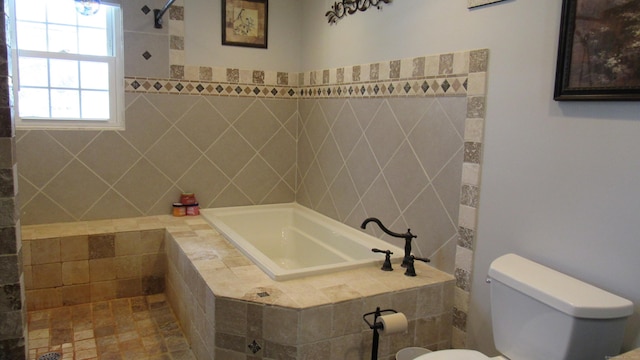 bathroom featuring tiled bath and toilet