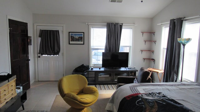 bedroom with multiple windows, lofted ceiling, and light tile patterned floors