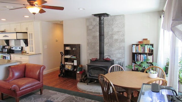 dining space with a wood stove, hardwood / wood-style floors, and ceiling fan