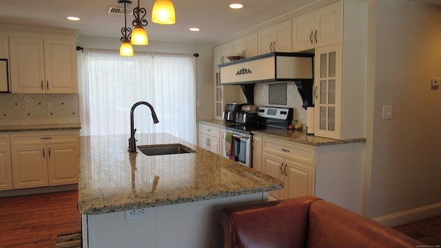 kitchen with sink, a center island with sink, electric range, and decorative light fixtures