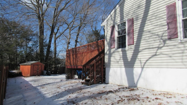 snow covered property featuring a deck and a storage unit