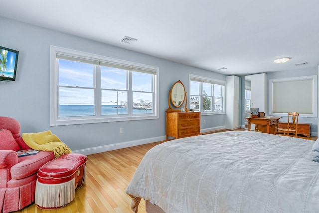 bedroom with a water view and light hardwood / wood-style floors