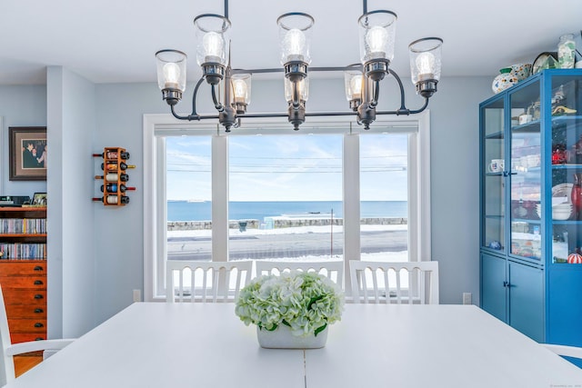 dining space featuring a water view, a chandelier, and a view of the beach