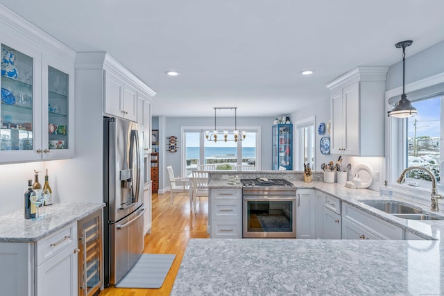 kitchen with white cabinetry, sink, stainless steel fridge with ice dispenser, and pendant lighting